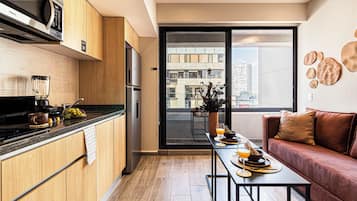 Een moderne keuken met houten kastjes, een ingebouwde magnetron en een eethoek met een tafel gedekt voor twee personen.