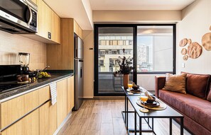 Une cuisine moderne avec des meubles en bois, un four à micro-ondes encastré et un coin repas avec une table mise pour deux personnes.