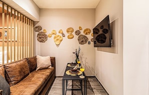 Un interior moderno con un sofá, una mesa con bebidas y decoración en la pared.