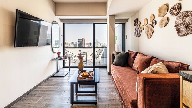 A modern living room with a sofa, a coffee table, and a flat-screen TV mounted on the wall. - Kukun Homero Polanco (Mexico City)
