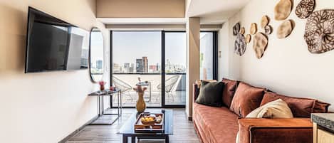 A modern living room with a sofa, a coffee table, and a flat-screen TV mounted on the wall.