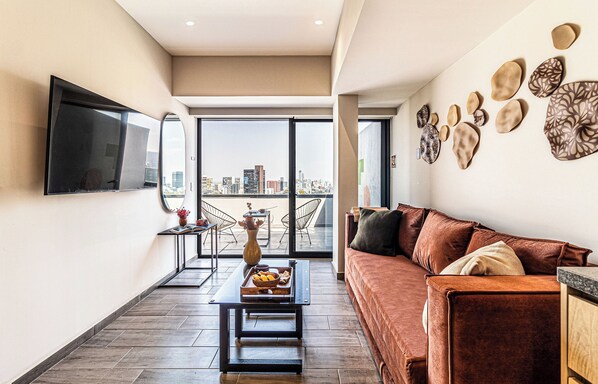 Un salon moderne avec un canapé, une table basse et un téléviseur à écran plat fixé au mur.