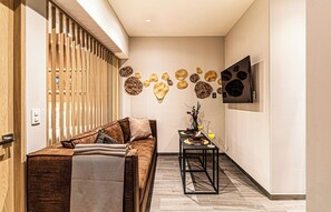 Ein modernes Interieur mit einer Couch, einem kleinen Tisch mit einer Vase und einem Glas, sowie dekorativer Wandkunst.