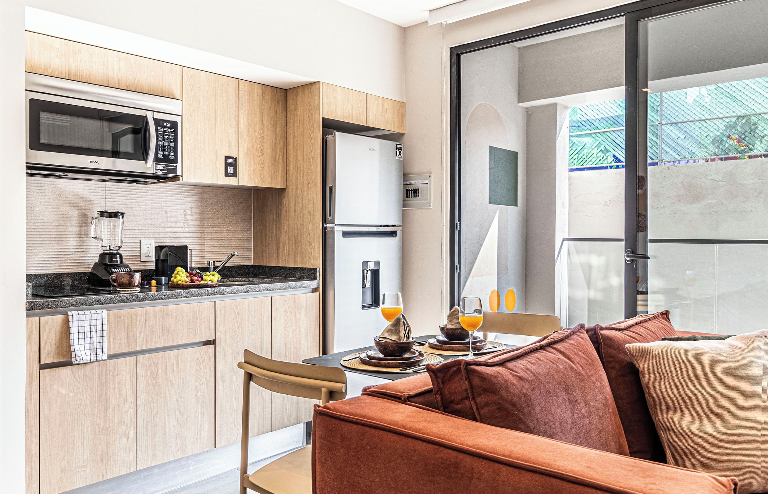 A modern kitchen with a microwave, refrigerator, and a dining area with a table set for two.