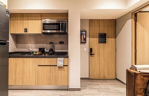 A compact kitchen with wooden cabinets, a built-in microwave, and a coffee maker.