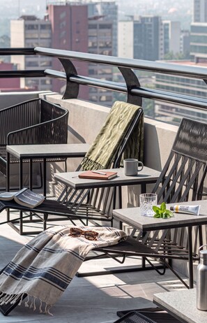 Une terrasse sur le toit, aménagée avec du mobilier d’extérieur, une table avec un livre, une tasse et un tube de crème solaire.