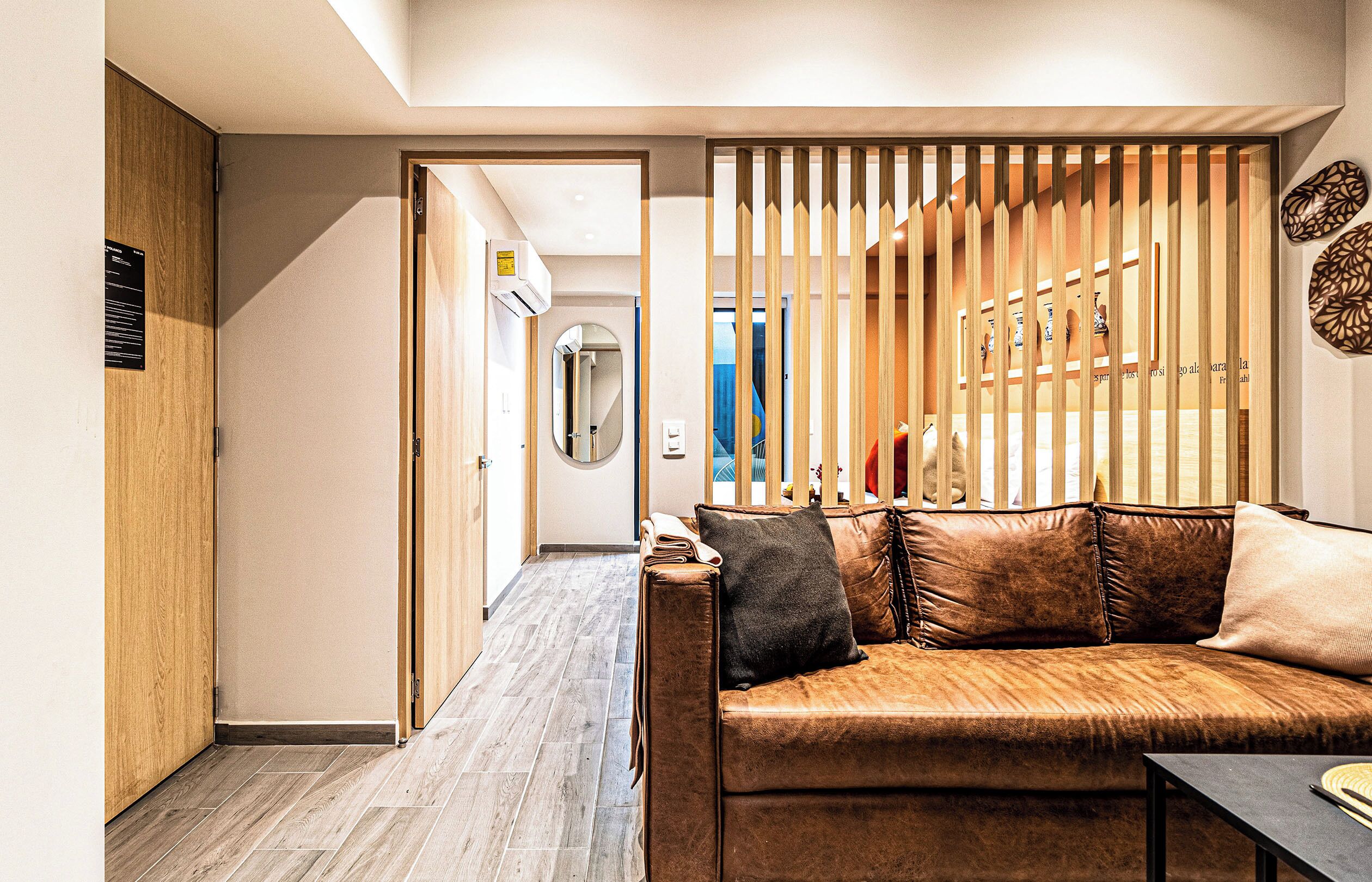 Un intérieur moderne avec un plancher en bois, un canapé avec des coussins et un panneau décoratif à lattes verticales.