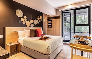 Een moderne slaapkamer met een groot bed, een houten hoofdeinde, een nachtkastje, een kledingkast en een kunstwerk aan de muur, plus een uitzicht op het groen door een groot raam.