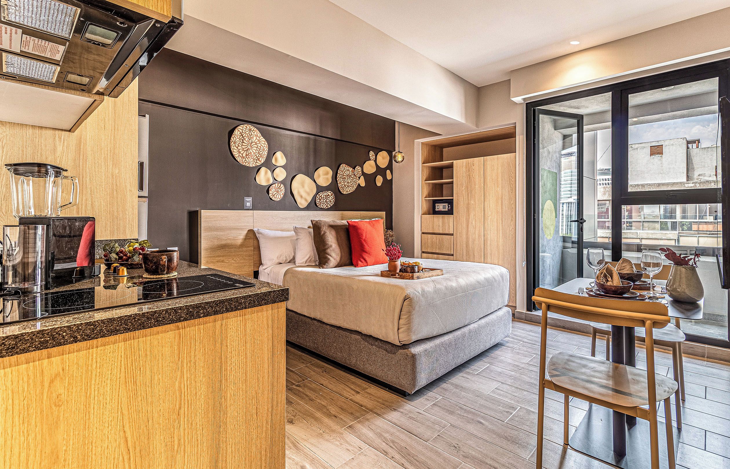 A modern bedroom with a bed, bedside table, and a dining area with a table and chairs.