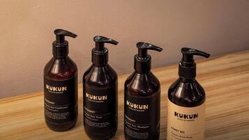 Four bottles of Kukun organic hair care products on a wooden surface.