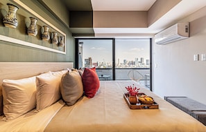 Een moderne hotelkamer met een groot bed, uitzicht over de stad en decoratieve vazen aan de muur.