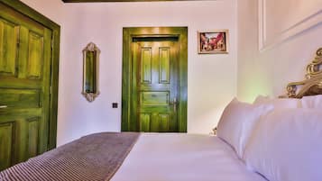 Habitación de hotel con una cama grande, una puerta verde, un espejo y un cuadro en la pared.