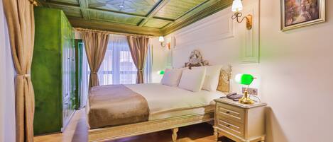 A bedroom with a bed, bedside table, lamp, and a painting on the wall.