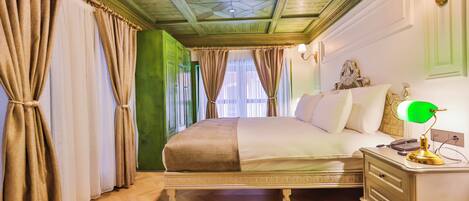 Un dormitorio con una cama grande, una mesita de noche con lámpara y una pared verde.