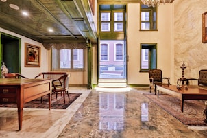 A spacious room with a marble floor, wooden furniture, and a view of a building through a large window.