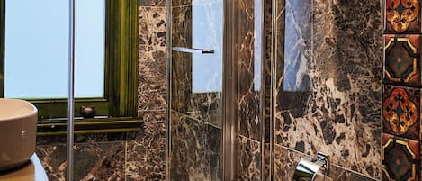 A bathroom with a marble floor, a glass shower enclosure, a toilet, and a sink.