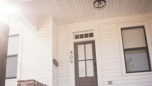A white house with a brown door and the number 409 on the wall. - Charming Meets Modern 2-bedroom Cottage (Morgan City)