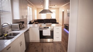 A modern kitchen with white cabinetry, stainless steel appliances, and a built-in oven. - Charming Meets Modern 2-bedroom Cottage (Morgan City)