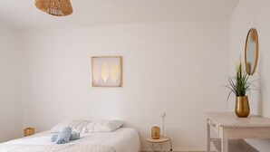 A minimalist bedroom with a bed, bedside table, and a small round table with a plant. - Aux Arènes, 30m from Les Arènes, Balcony, AC (Nîmes)