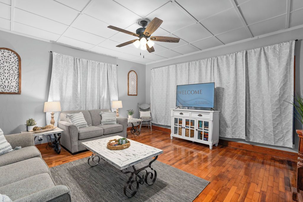 A living room with a ceiling fan, a television, a white cabinet, and a grey sofa.