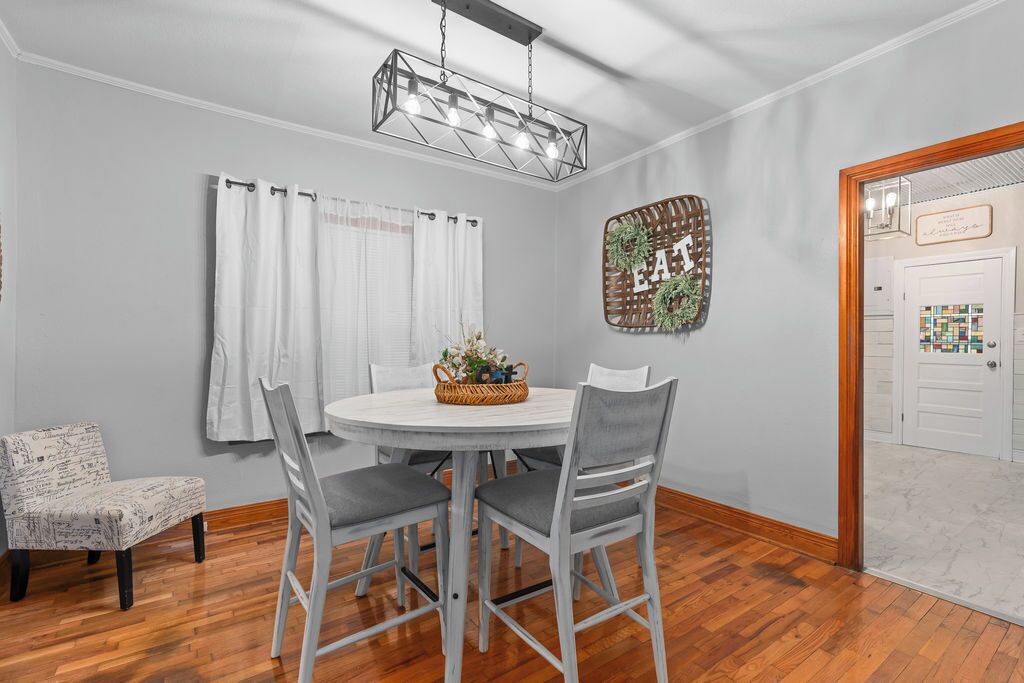 A dining area with a round table, four chairs, a chandelier, and a wall-mounted sign.