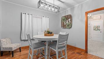A dining area with a round table, four chairs, a chandelier, and a wall-mounted sign.