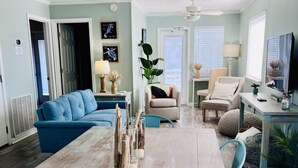 Un salón amplio con una gran mesa de comedor de madera, un sofá azul y un sillón beige.