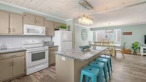 Een moderne keuken met een centraal eiland, houten kasten en een eetgedeelte met uitzicht.