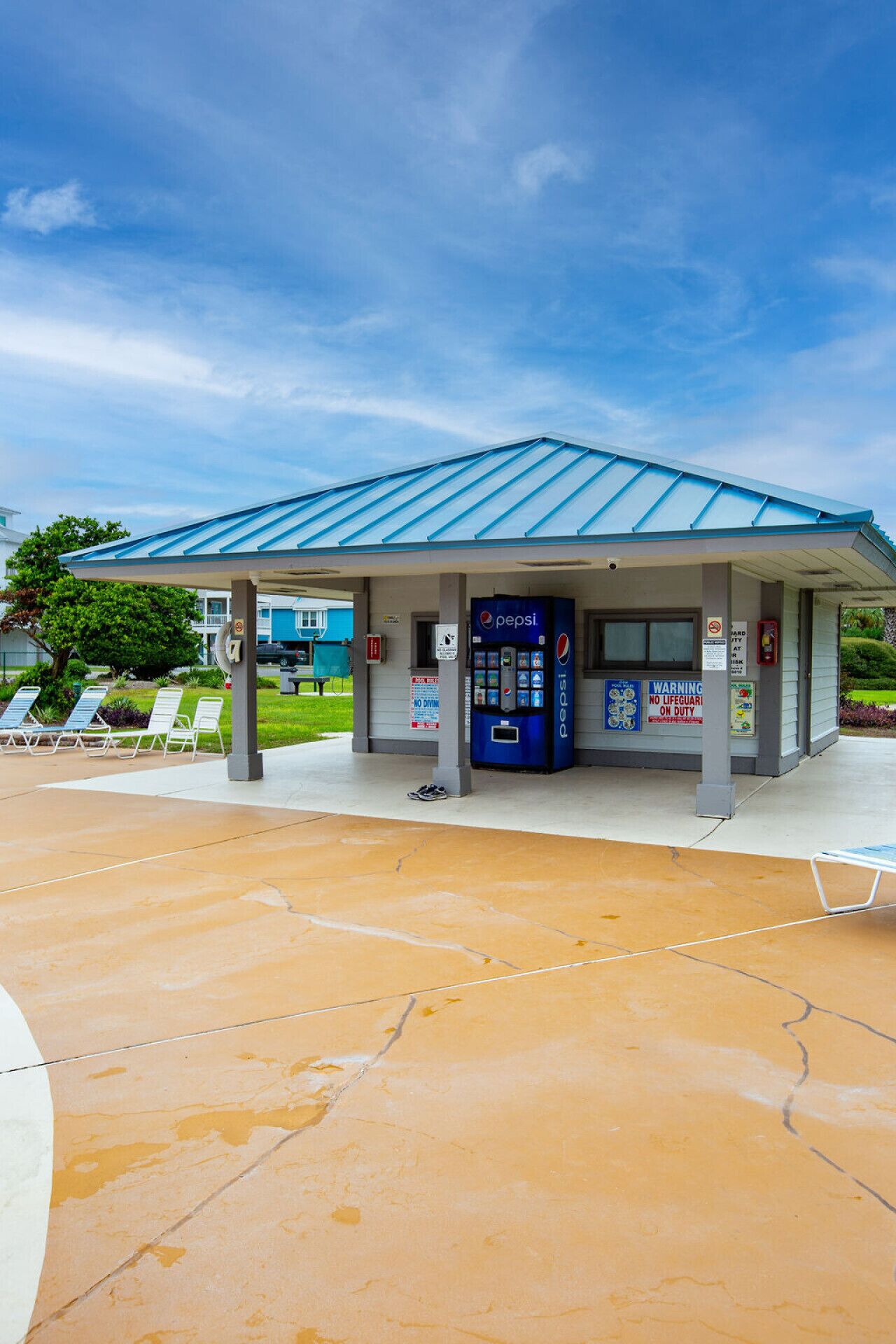 A gas station with a blue roof, a Pepsi vending machine, and a covered seating area with lounge chairs.