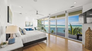 A modern bedroom with a large bed, a ceiling fan, and a view of the ocean. - Endless Horizon in Siesta Key (Siesta Key)