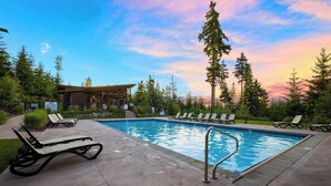 A pool area with lounge chairs, a wooden building, and a view of trees and a sunset. - 3 Bedroom w/ Game Room / Gourmet Kitchen / Community Pool - MNT VIEW IS AMAZING! (Cle Elum)