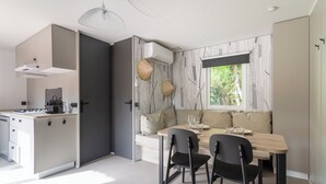 Une cuisine moderne avec un coin repas, comprenant une cuisinière intégrée, des meubles de rangement blancs et une table à manger avec des chaises.