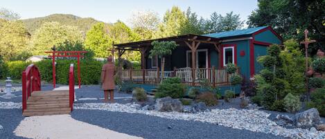A rustic cabin with a wooden deck and a red entrance gate.