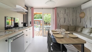 Une cuisine moderne dotée d’un plan de travail en bois, d’appareils électroménagers en acier inoxydable et d’un coin repas avec une table et des chaises en bois.