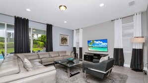 Una sala moderna con sofá, mesa de centro, televisor y cortinas.