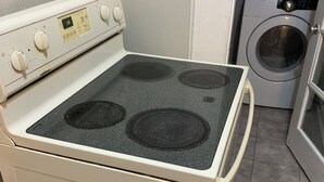 A kitchen with a white stove, a washing machine, and a microwave. - Lenny's Southy Hostel (St. Petersburg)