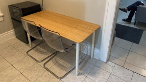 A small office space with a wooden desk, two clear plastic chairs, a black filing cabinet, and a white door. - Lenny's Southy Hostel (St. Petersburg)