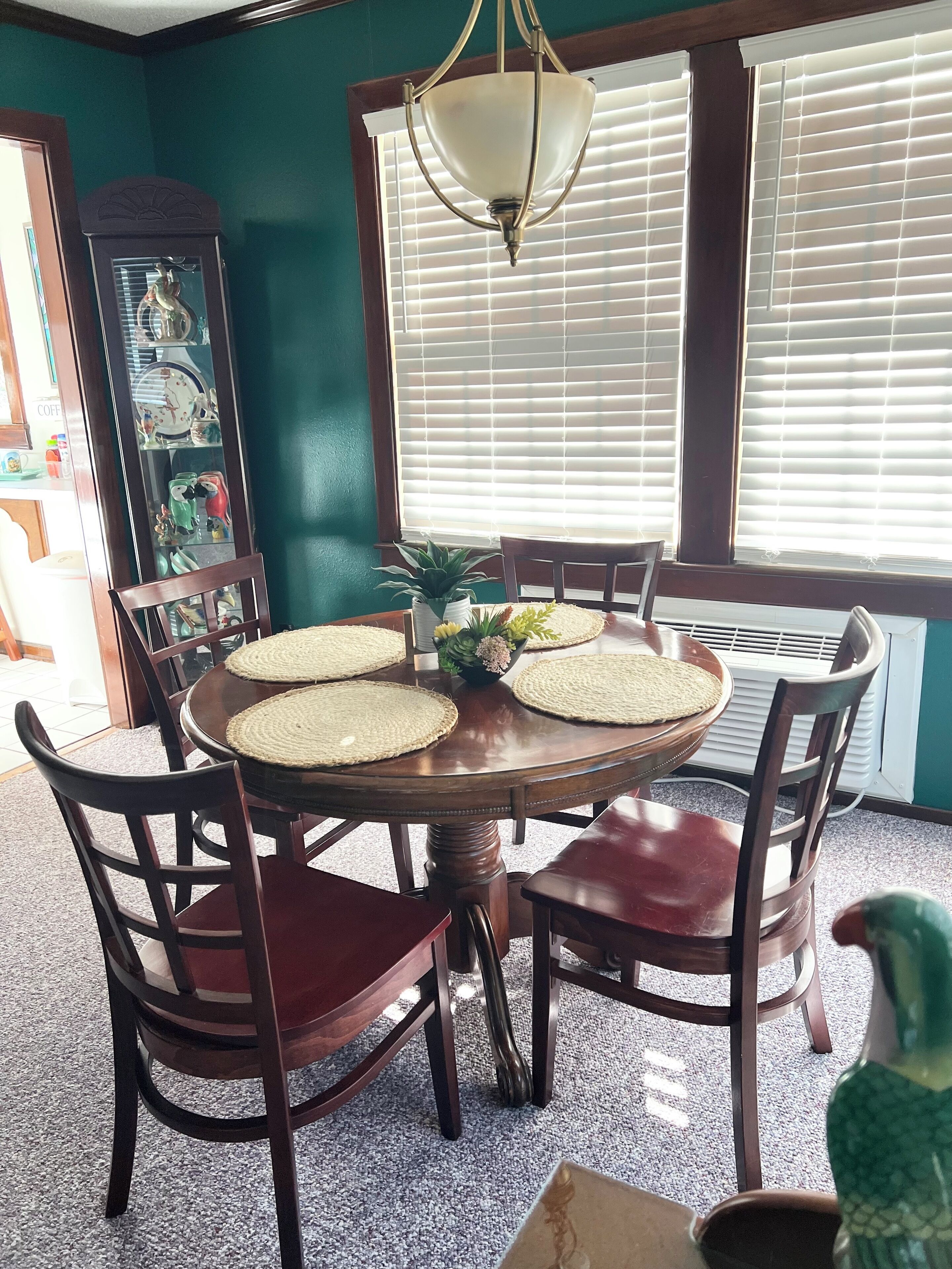A dining area with a round table, six chairs, and a decorative ceiling light.