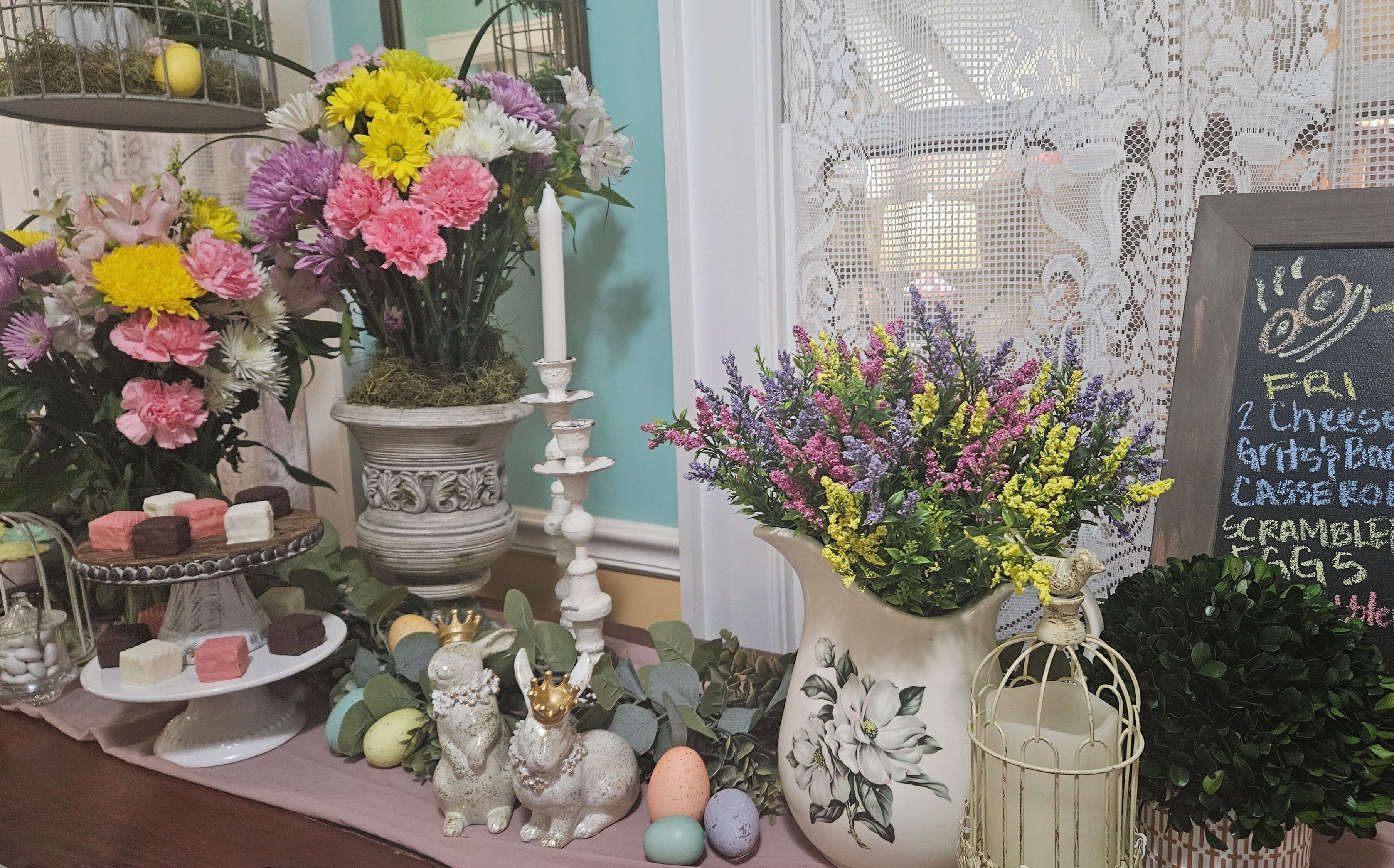 A table with various decorative items including flowers, candles, and figurines.