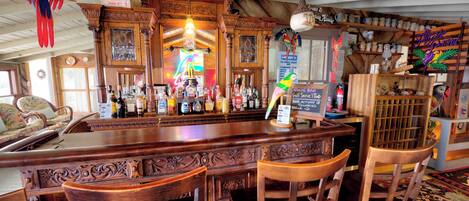 A bar area with wooden bar counter, bar stools, and various bottles.