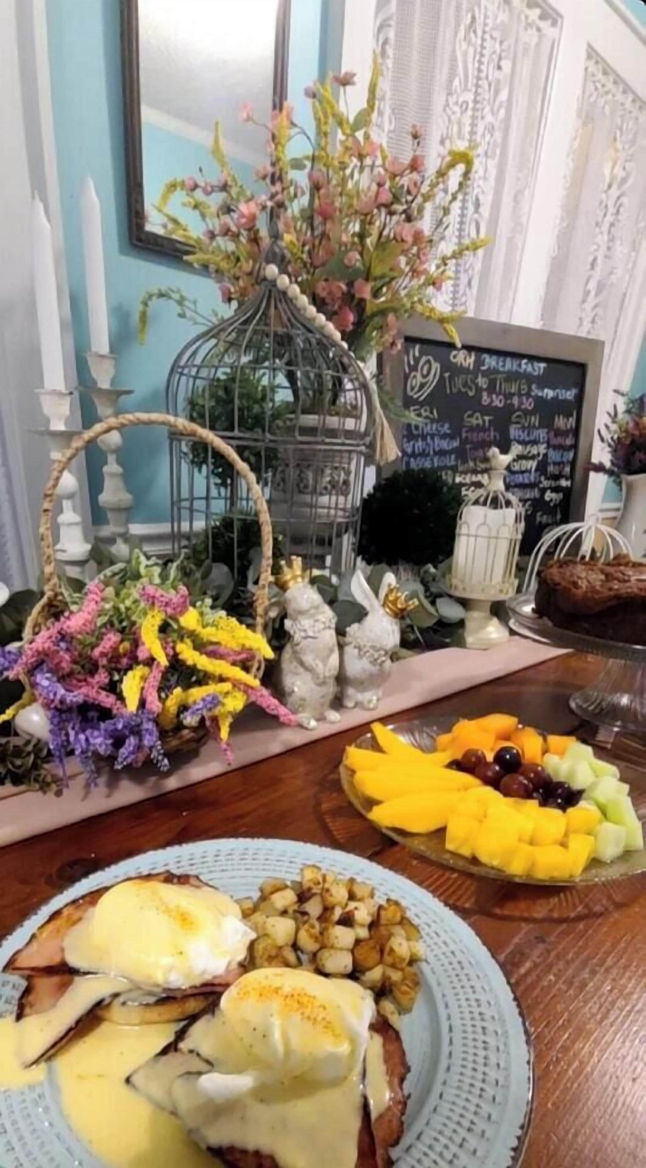 A breakfast table with a variety of food items, including eggs Benedict, fruit, and pastries.