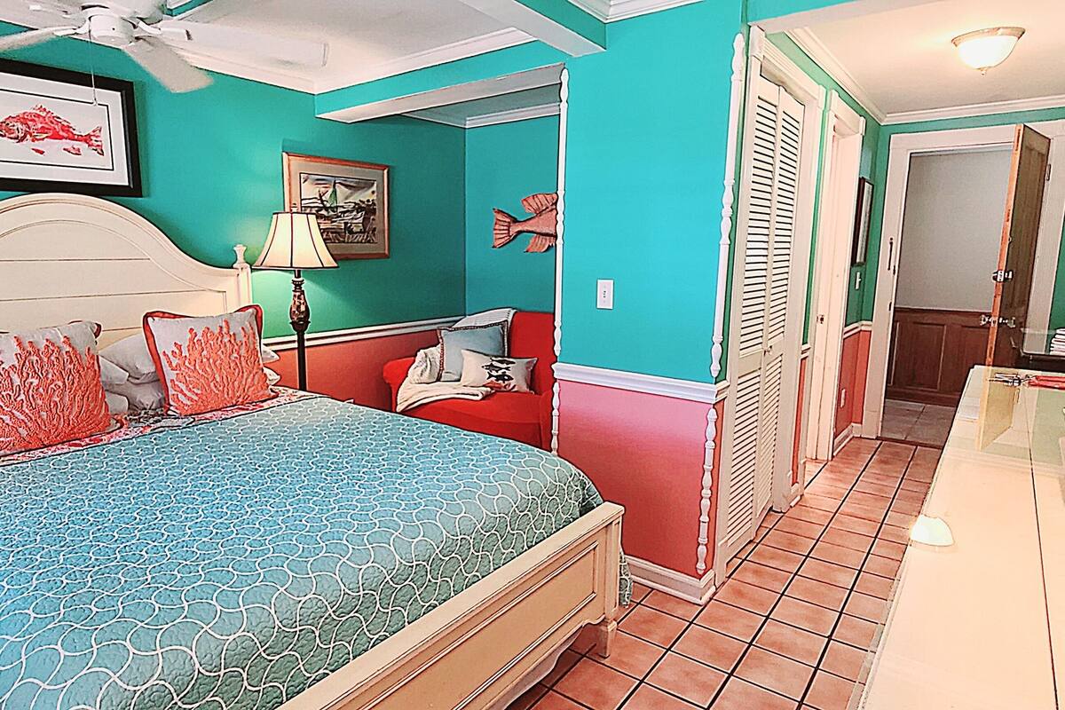 A bedroom with a bed, a nightstand, a lamp, and a dresser.