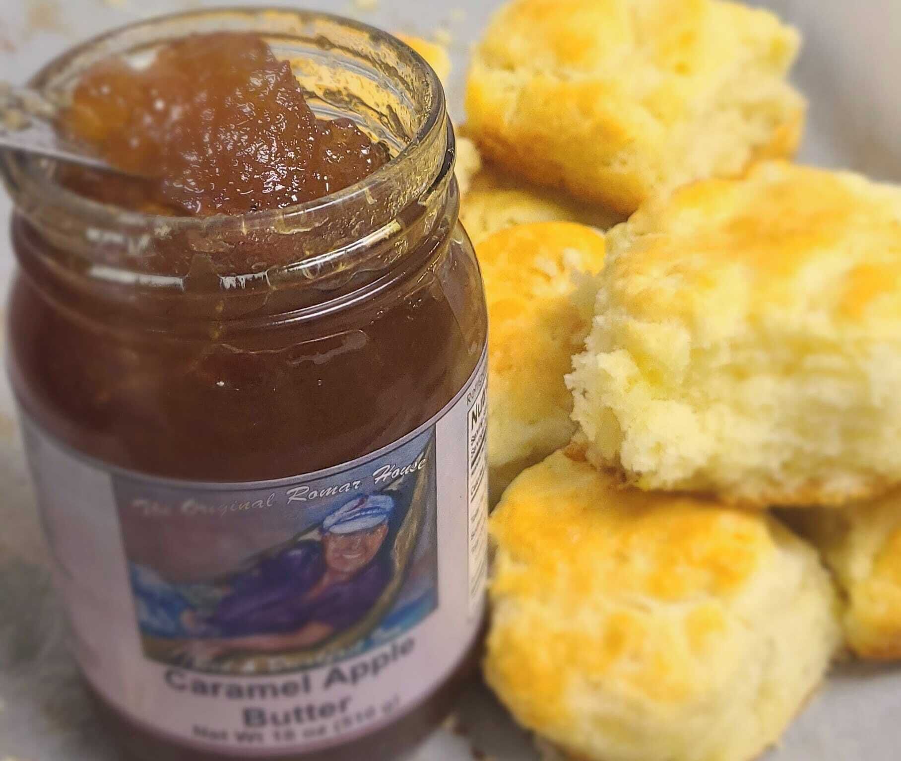 A jar of caramel apple butter next to biscuits.
