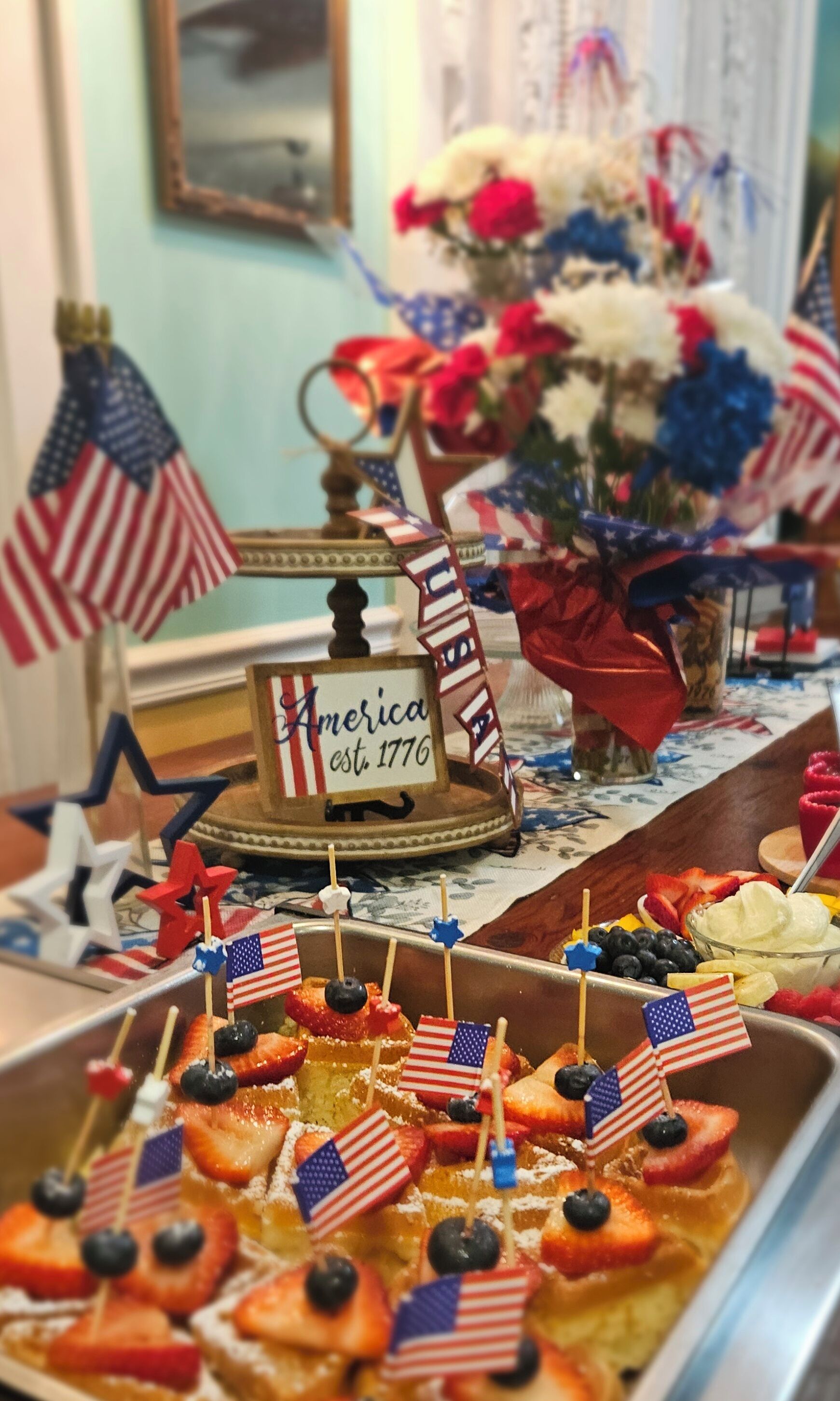 A dessert table with American flags and a sign reading "America est. 1776".