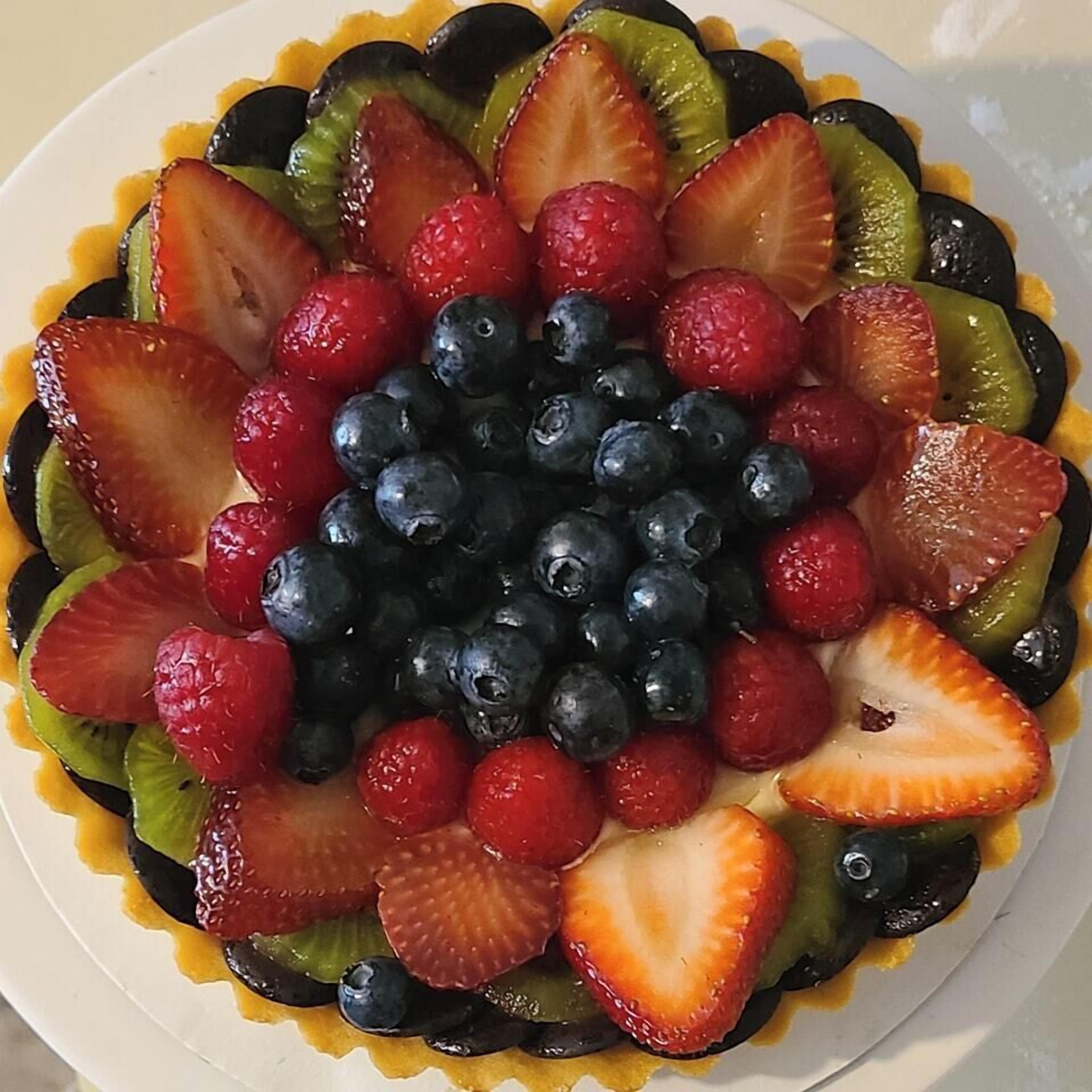 Une tarte aux fruits garnie de fraises, de myrtilles et de tranches de kiwi.