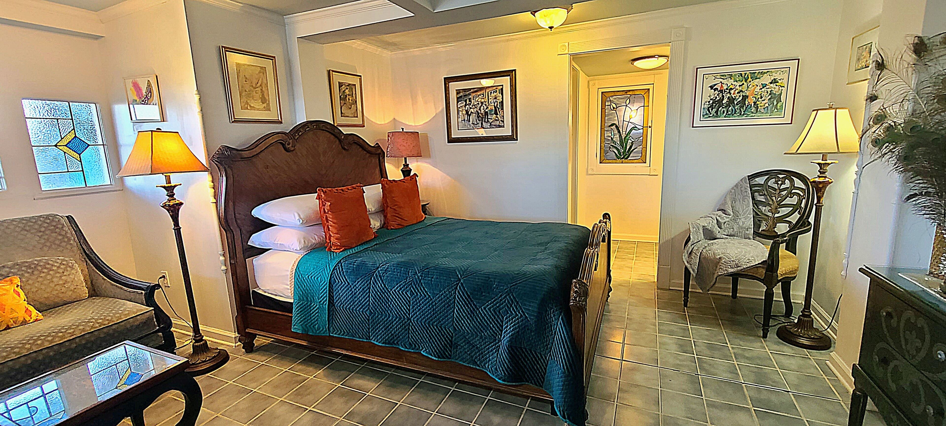 Een slaapkamer met een groot bed, een stoel, een dressoir en een lamp.