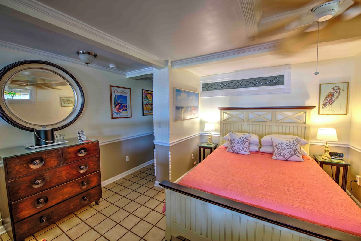 A bedroom with a bed, dresser, and a round mirror.