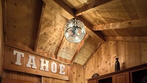 Ett rum med träpanel, en säng, ett nattduksbord med en lampa, en hylla med dekorativa föremål och en skylt med texten ”TAHOE”.