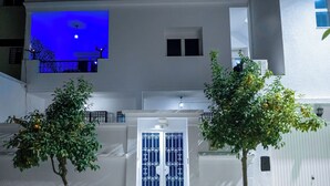 A building with a white facade, a blue door with decorative patterns, and two potted trees with green foliage and yellow fruits. - CASABLU Apparte - Cozy blue terrace, Sunset view (Nabeul‎)