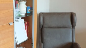 A room with a grey armchair, wooden cabinet with glass doors, and a white wall. - Zimmer in Centrum von Berlin (Berlin)